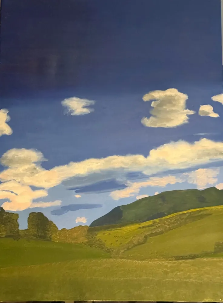 Clouds over the Valley: thick white clouds in a deep blue sky above green hills